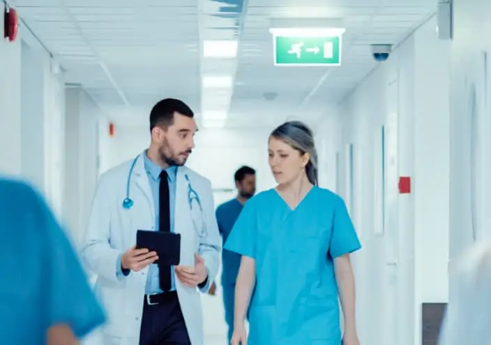Un couloir d'hôpital avec plusieurs praticiens marchant