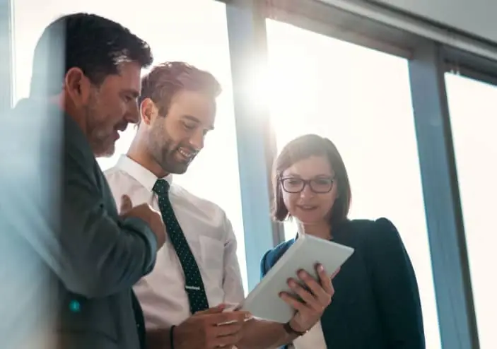 Trois personnes de la finance regardent une tablette ensemble